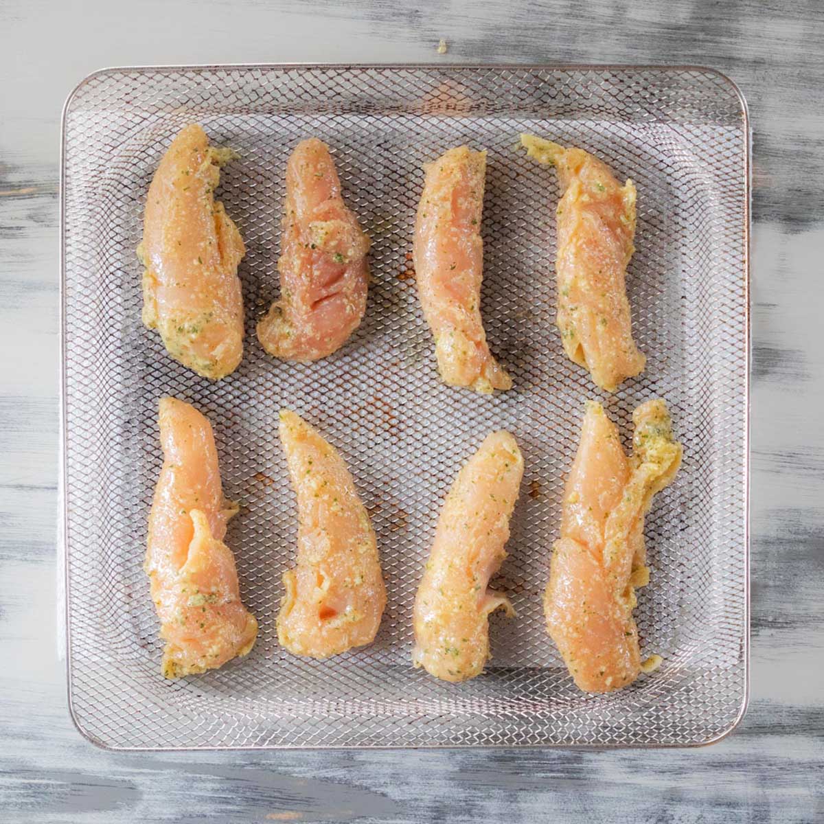 Six chicken tender on a metal tray.